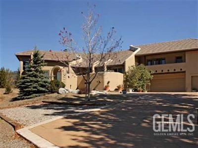 view of front facade featuring an attached garage, driveway, and stucco siding