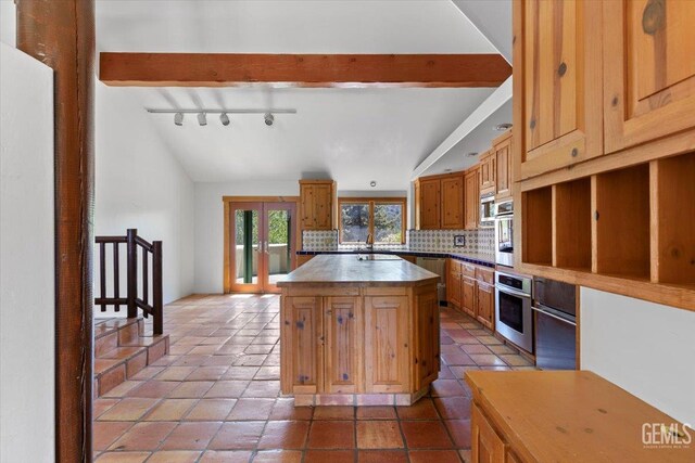 28221 Cumberland Rd, Tehachapi, CA 93561 - kitchen with stainless steel oven, tasteful backsplash, a kitchen island, brown cabinetry, and a sink