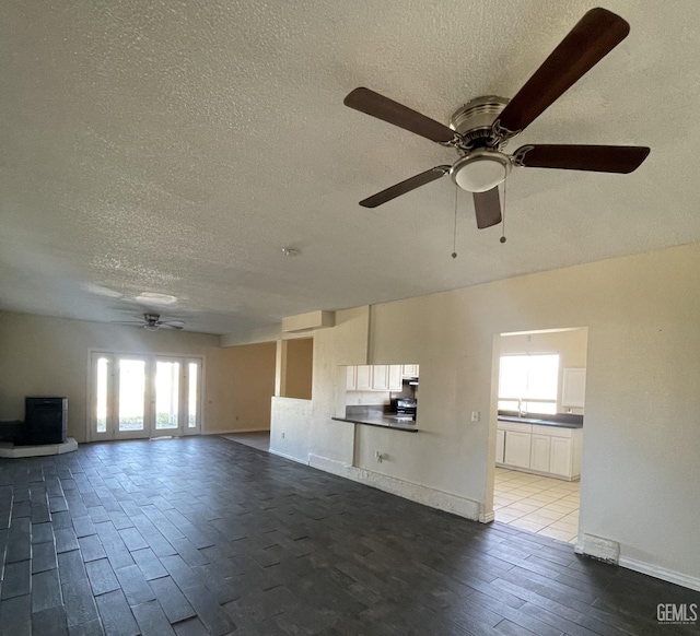 unfurnished living room with wood-type flooring, a textured ceiling, ceiling fan, and sink