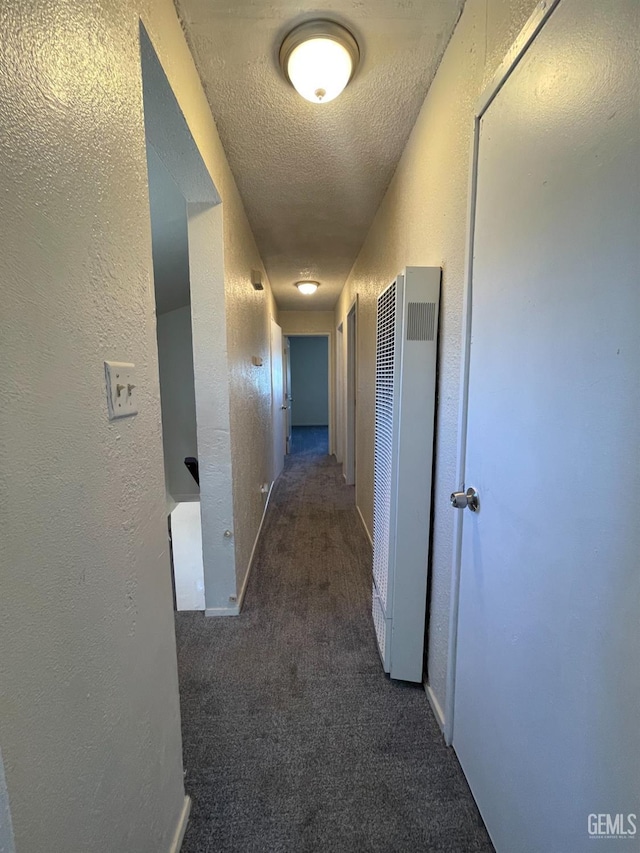 hall with dark colored carpet and a textured ceiling