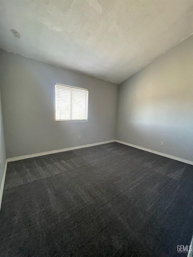 unfurnished room with a textured ceiling and dark carpet