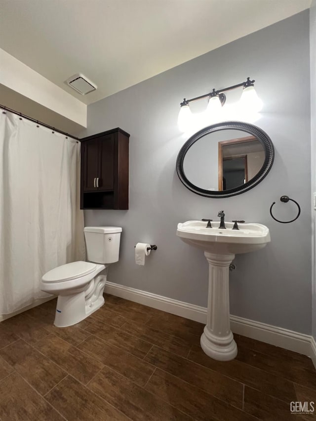 bathroom featuring baseboards, toilet, and wood finished floors