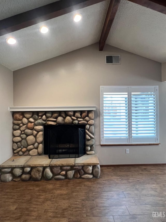 detailed view of beam ceiling, a textured ceiling, wood finished floors, recessed lighting, and a stone fireplace