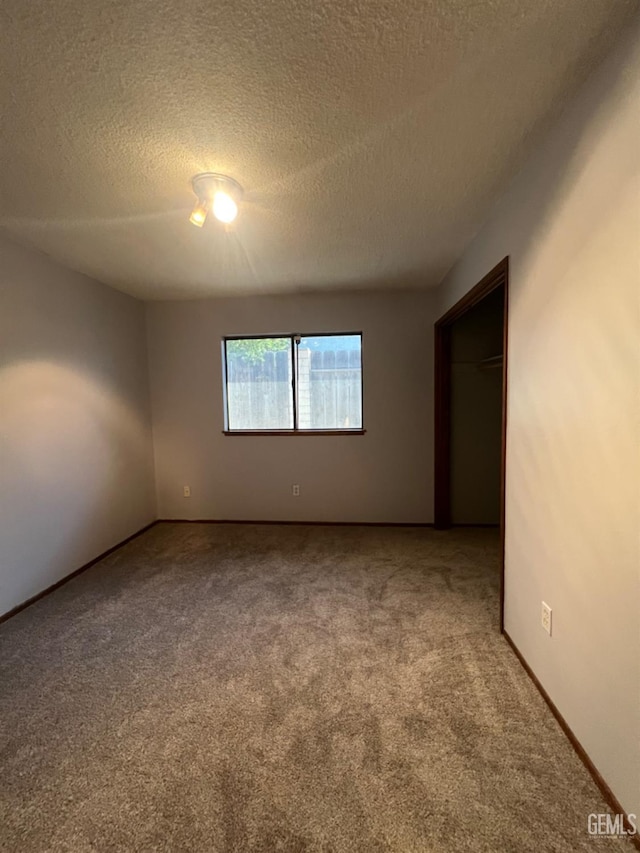 unfurnished bedroom with carpet, a textured ceiling, and baseboards