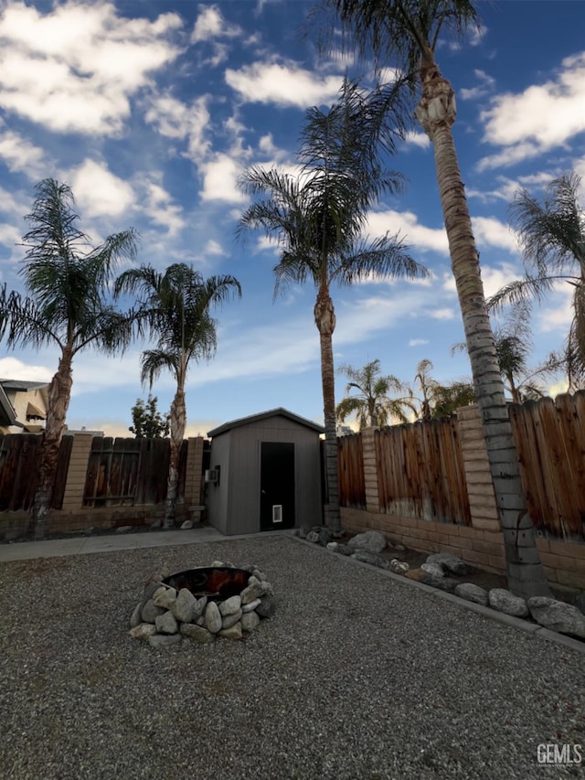 exterior space with a shed, an outdoor fire pit, a fenced backyard, and an outbuilding