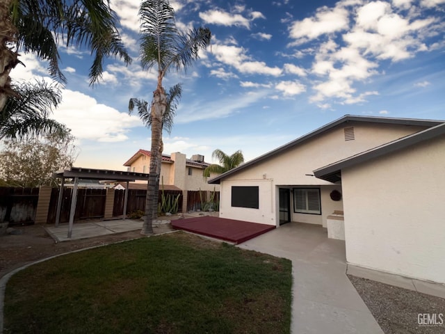 rear view of house with stucco siding, a patio area, a pergola, and a wooden deck