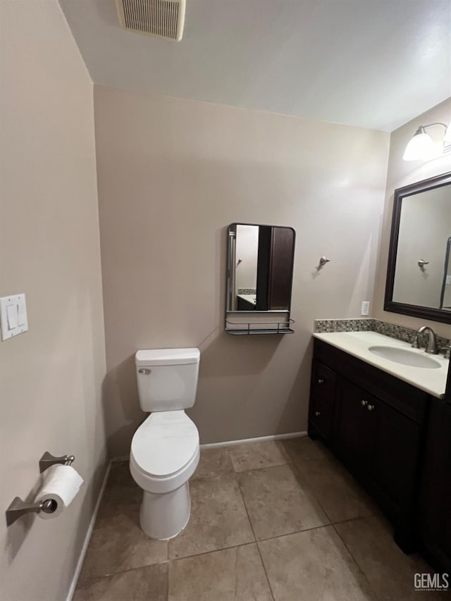 half bath featuring toilet, tile patterned flooring, vanity, and baseboards