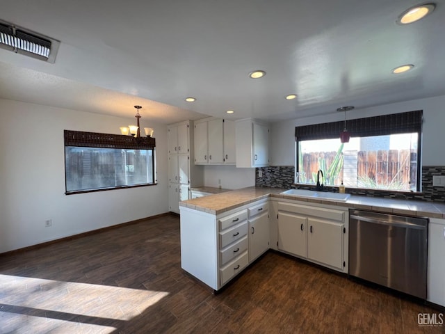 kitchen featuring dishwasher, a sink, a chandelier, white cabinets, and a peninsula