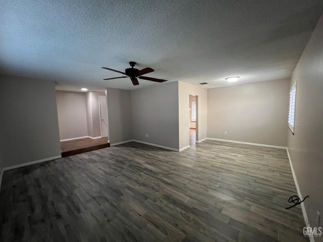 unfurnished room with dark wood finished floors, ceiling fan, baseboards, and a textured ceiling