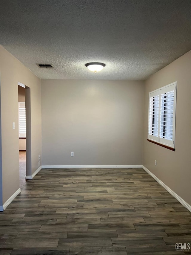 unfurnished room with dark wood-style floors, baseboards, and a textured ceiling