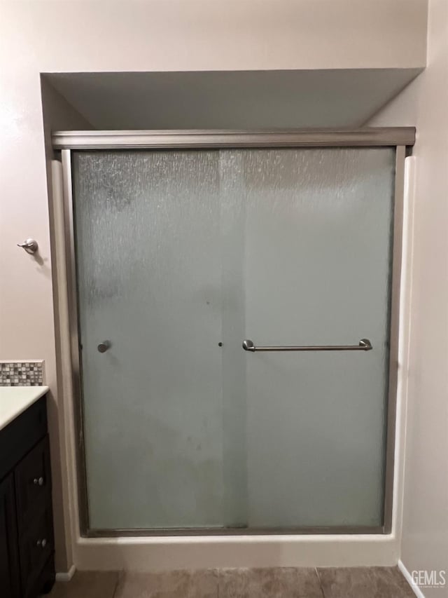 full bathroom featuring a stall shower, vanity, and tile patterned flooring