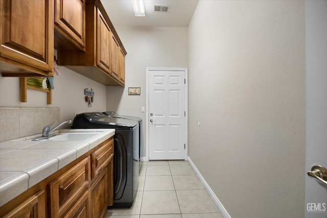 laundry room featuring cabinets, washer and dryer, sink, and light tile patterned floors