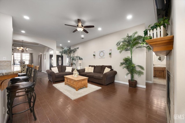 living room with dark wood-type flooring and ceiling fan with notable chandelier