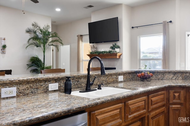 kitchen with stone countertops, sink, stainless steel dishwasher, and ceiling fan