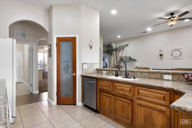 kitchen featuring white refrigerator, dishwasher, sink, and light stone countertops