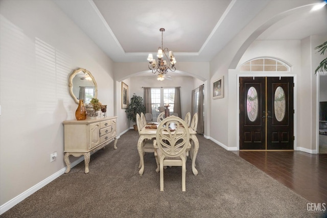 dining room with a raised ceiling, dark hardwood / wood-style floors, and an inviting chandelier