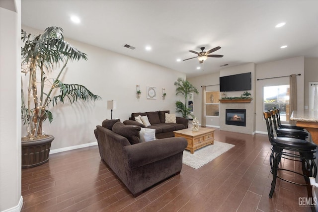 living room with dark hardwood / wood-style floors, a fireplace, and ceiling fan