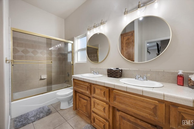 full bathroom with tile patterned flooring, vanity, combined bath / shower with glass door, and toilet