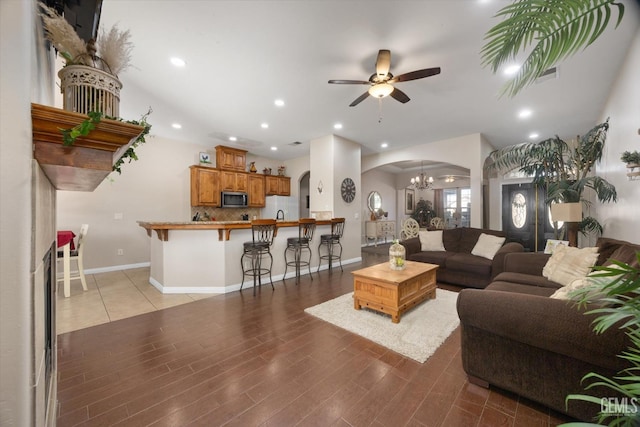 living room featuring ceiling fan with notable chandelier and light hardwood / wood-style floors