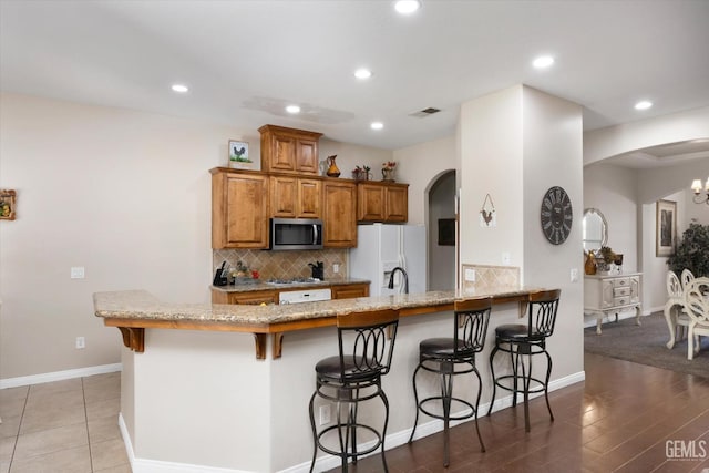 kitchen featuring appliances with stainless steel finishes, backsplash, a kitchen breakfast bar, and kitchen peninsula