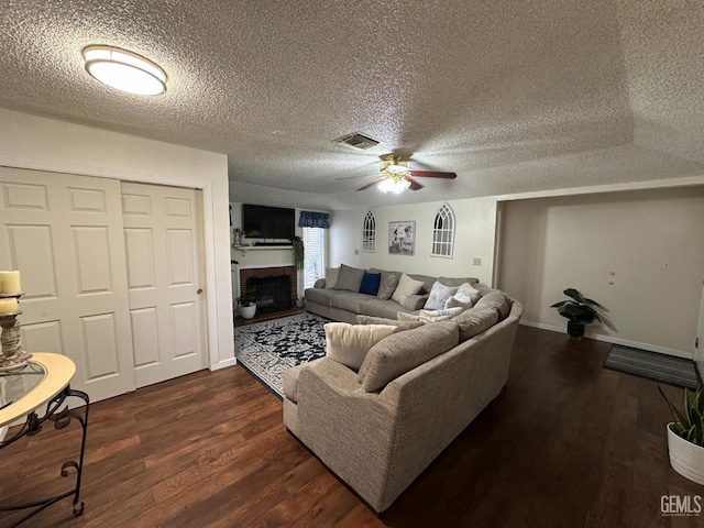 1022 9th Ave, Delano, CA 93215 - living area with ceiling fan, dark wood-style flooring, a brick fireplace, and a textured ceiling