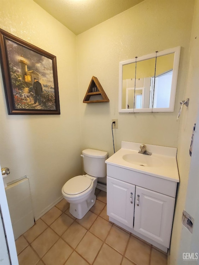 bathroom with toilet, vanity, and tile patterned flooring