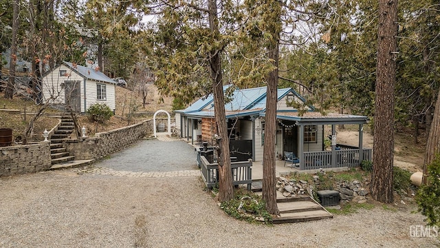 view of front of house featuring stairway, a porch, metal roof, and driveway