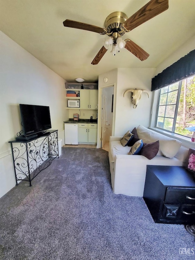 living area featuring ceiling fan and dark colored carpet