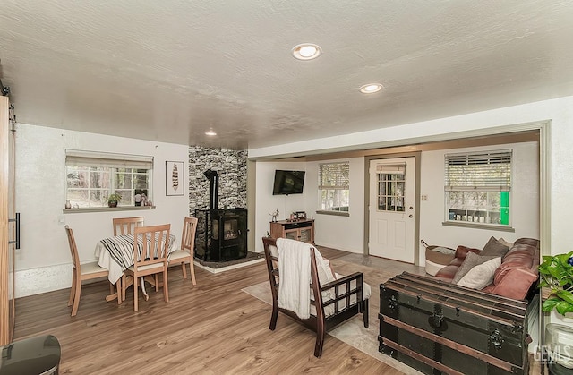 living room with a wood stove, recessed lighting, light wood-style floors, and a textured ceiling