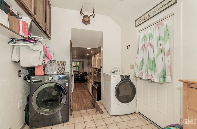 laundry area featuring washer and dryer, light tile patterned floors, and cabinet space