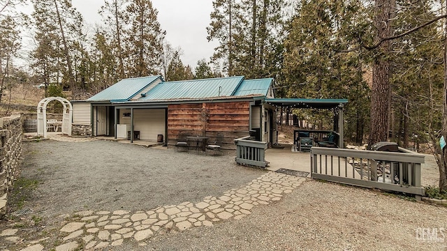 back of property with metal roof and a patio