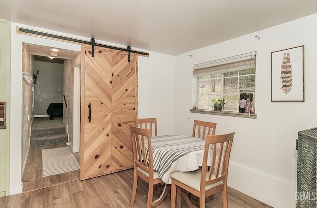 dining room with a barn door and wood finished floors
