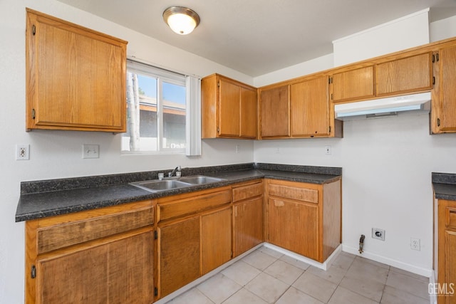 132 E Center St, Taft, CA 93268 - kitchen with under cabinet range hood, brown cabinetry, dark countertops, and light tile patterned flooring
