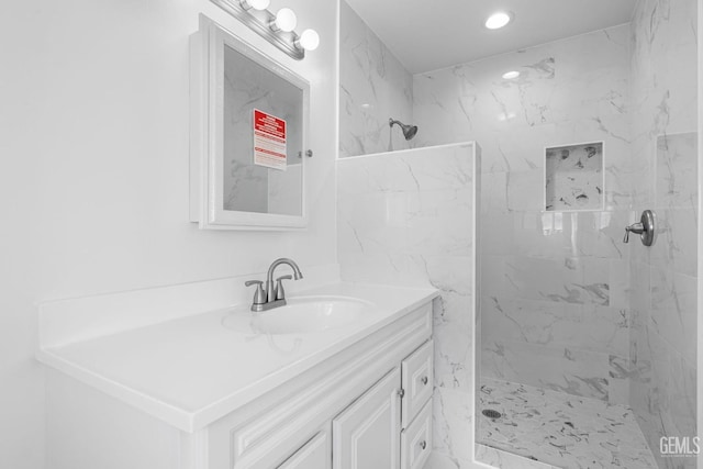 bathroom with a tile shower and vanity