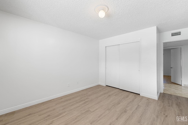 unfurnished bedroom with a closet, light hardwood / wood-style floors, and a textured ceiling