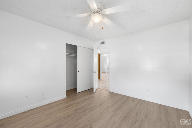 unfurnished bedroom featuring ceiling fan, a closet, a textured ceiling, and light hardwood / wood-style flooring