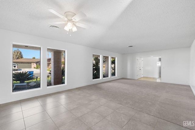 empty room with light carpet, ceiling fan, and a textured ceiling