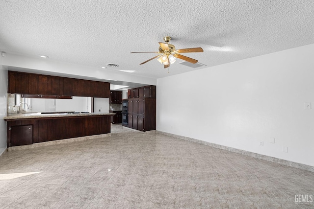 kitchen with kitchen peninsula, a textured ceiling, ceiling fan, and sink