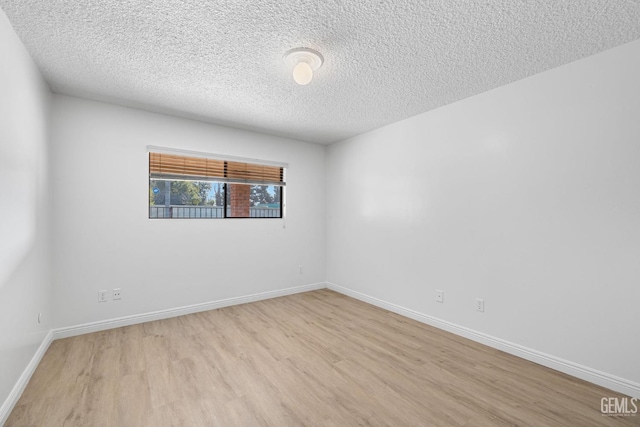 spare room with a textured ceiling and light hardwood / wood-style flooring