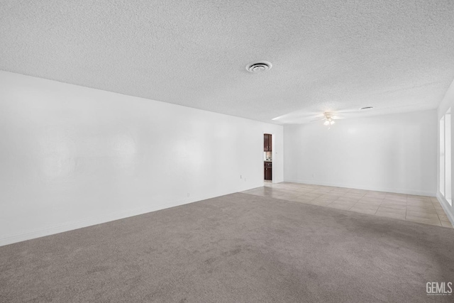 empty room featuring light carpet, a textured ceiling, and ceiling fan