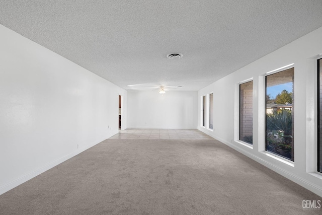 spare room featuring a textured ceiling, ceiling fan, and light carpet