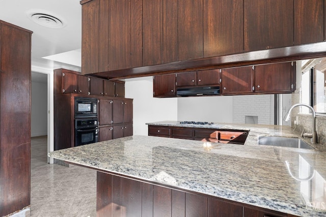 kitchen featuring kitchen peninsula, light stone countertops, black appliances, and sink