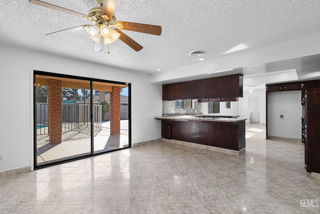 kitchen featuring kitchen peninsula, decorative backsplash, dark brown cabinets, a textured ceiling, and ceiling fan