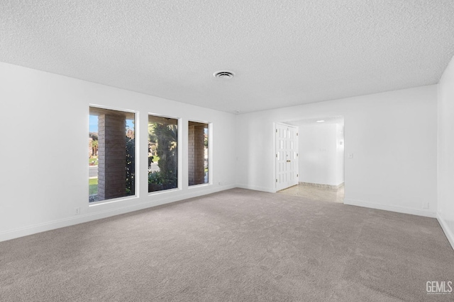 spare room with light carpet and a textured ceiling