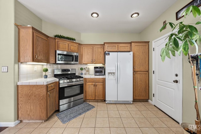 2109 Via Tuscania Ave, Delano, CA 93215 - kitchen featuring appliances with stainless steel finishes, tile countertops, decorative backsplash, and brown cabinetry