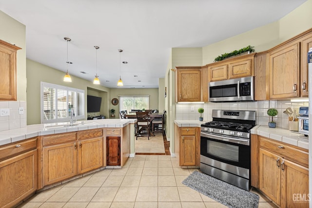 2109 Via Tuscania Ave, Delano, CA 93215 - kitchen featuring appliances with stainless steel finishes, a sink, tile countertops, tasteful backsplash, and light tile patterned floors