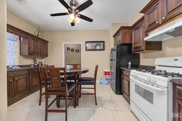 2109 Via Tuscania Ave, Delano, CA 93215 - kitchen featuring white gas range, a ceiling fan, freestanding refrigerator, under cabinet range hood, and dark brown cabinetry
