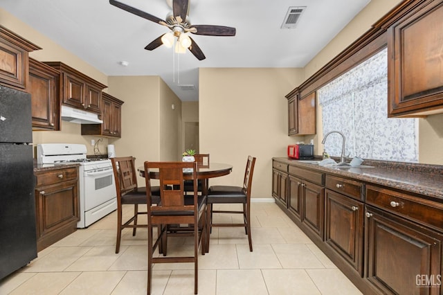 2109 Via Tuscania Ave, Delano, CA 93215 - kitchen featuring white gas range, freestanding refrigerator, a sink, and dark countertops