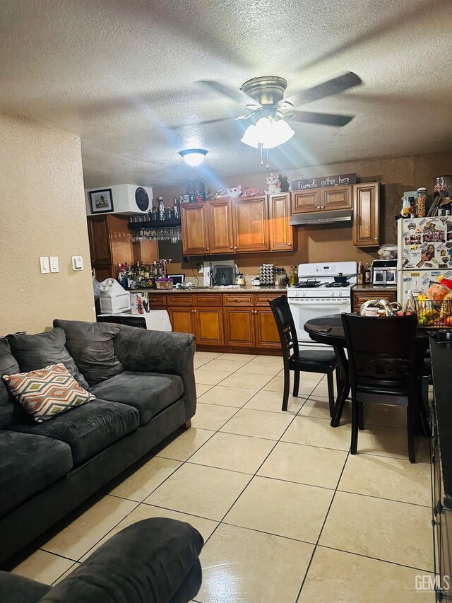 kitchen featuring light tile patterned flooring, white appliances, and a textured ceiling