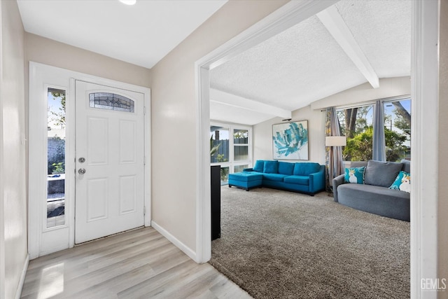 foyer entrance featuring a textured ceiling, light hardwood / wood-style flooring, lofted ceiling with beams, and a healthy amount of sunlight